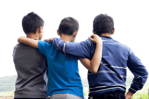 three young boys with their arms wrapped around each other