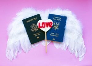 two passports laying on top of white feather angel wings